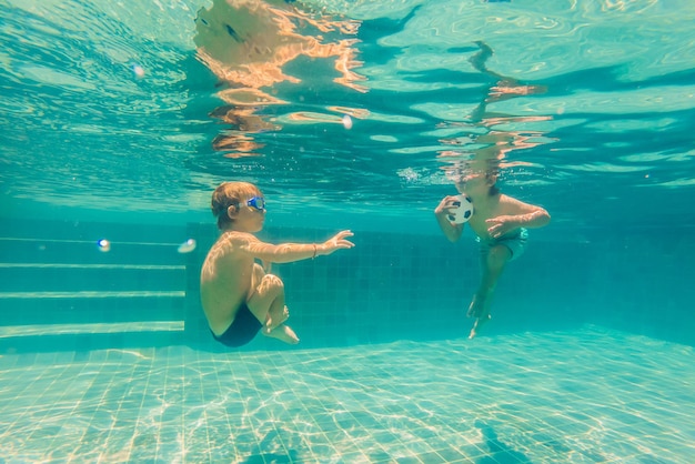 Due bambini che si tuffano con le maschere sott'acqua in piscina.