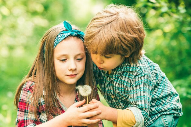 Due bambini che soffiano il dente di leone nel parco Godetevi la natura