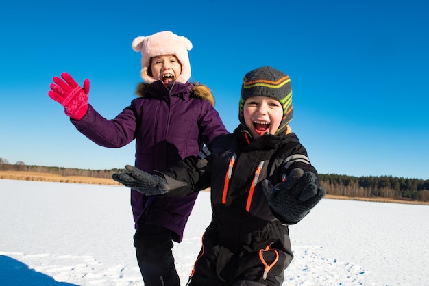 Due bambini felici che si divertono sulla neve nella soleggiata giornata invernale