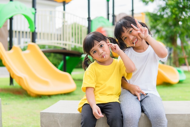 Due bambini giocano e mangiano lecca-lecca nel parco giochi