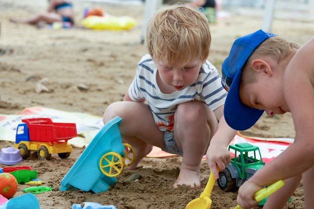 Due bambini giocano nella sabbia con giocattoli di plastica