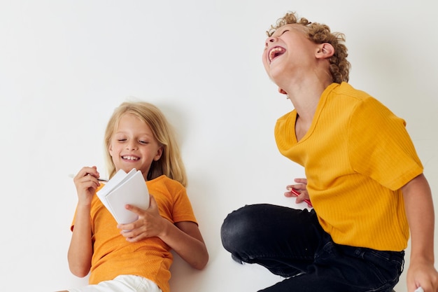 Due bambini gioiosi che disegnano giochi divertenti con lo stile di vita dell'infanzia del blocco note inalterato