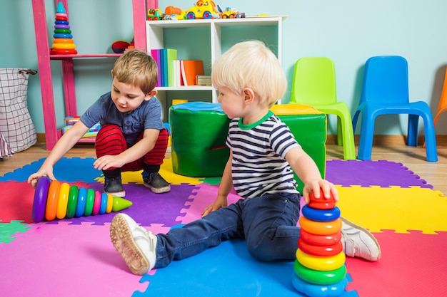 Due bambini in età prescolare compongono piramidi colorate Si siedono per terra all'asilo e comunicano