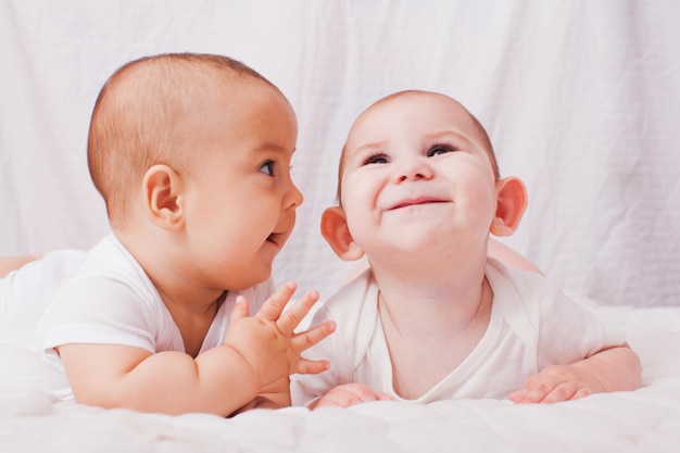 Due bambini sdraiati su una coltre bianca I gemelli stanno comunicando