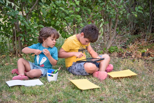 Due bambini studenti seduti a guardare il taccuino nel parco Concetto di primavera e vita di strada