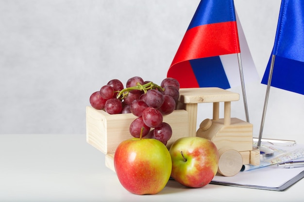 Due bandiere UE-Russia e un camion di legno pieno di uva. Due mele sullo sfondo