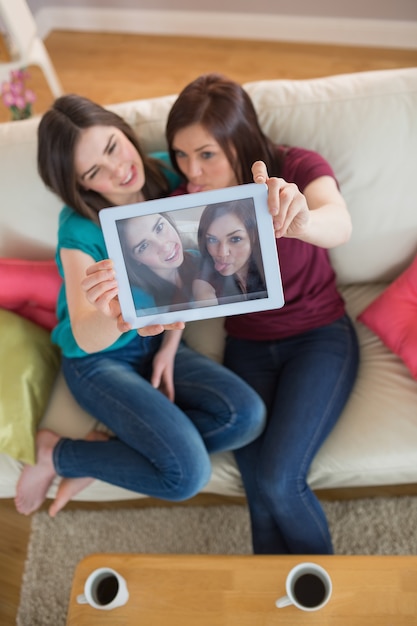 Due bei amici sul divano prendendo un selfie con tablet pc