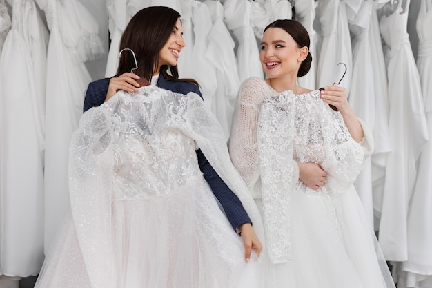 Due belle damigelle d'onore di un'amica scelgono un vestito da sposa nel salone.