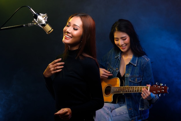 Due belle donne asiatiche cantante cantano canzoni e suonano la chitarra sul palco del caffè