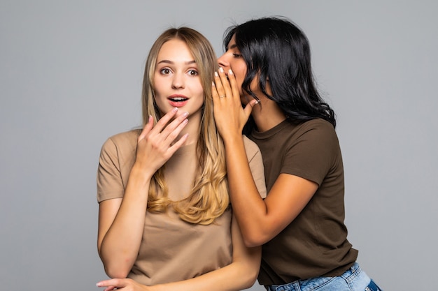 Due belle donne che raccontano il segreto. Isolato su muro bianco