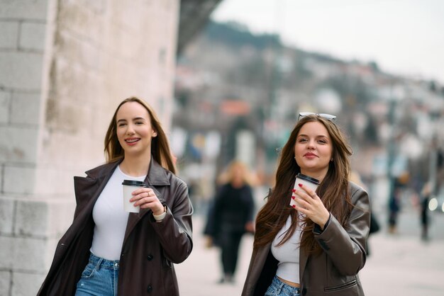 Due belle donne d'affari vanno al lavoro con una tazza di caffè in mano.