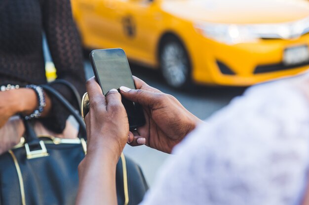 Due belle donne di colore che utilizzano Smart Phone a New York