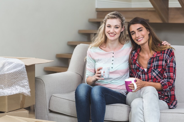 Due belle donne sedute fianco a fianco con una tazza di caffè