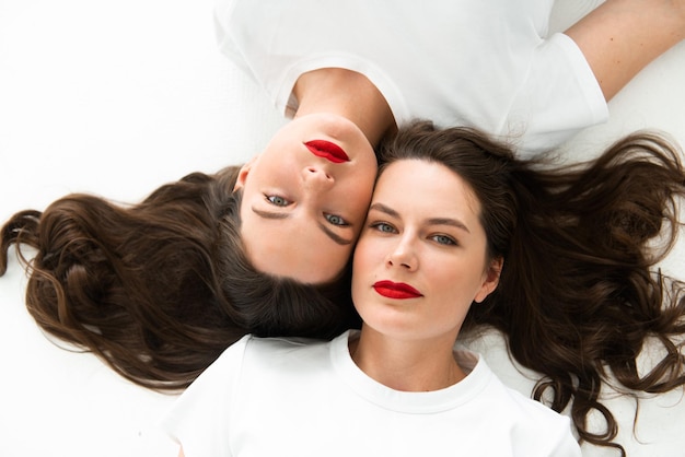 Due belle donne sorelle gemelle closeup viso ritratto posa sul pavimento