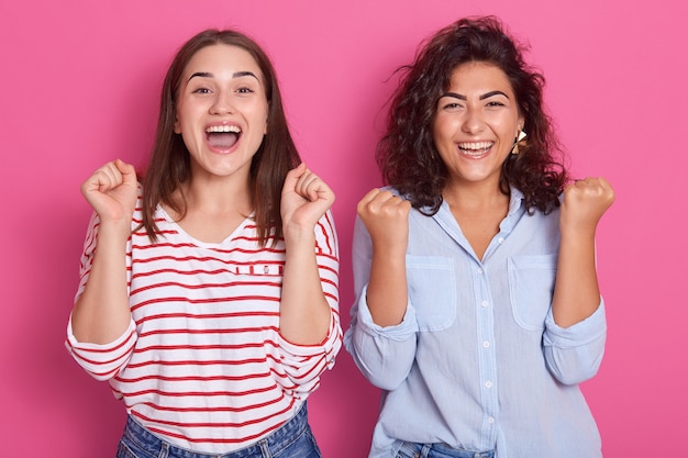 Due belle donne stringono i pugni con gioia ed entusiasmo. La gioia della vittoria e della felicità