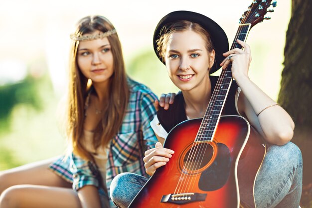 Due belle giovani donne a suonare la chitarra durante un picnic