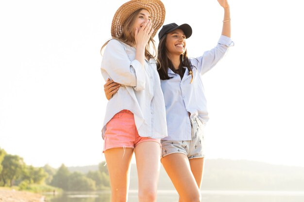 Due belle giovani donne che passeggiano su una spiaggia. Amiche che camminano sulla spiaggia e ridono in una giornata estiva.