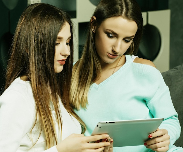 Due belle giovani donne che si rilassano sul pavimento del soggiorno guardando un computer portatile