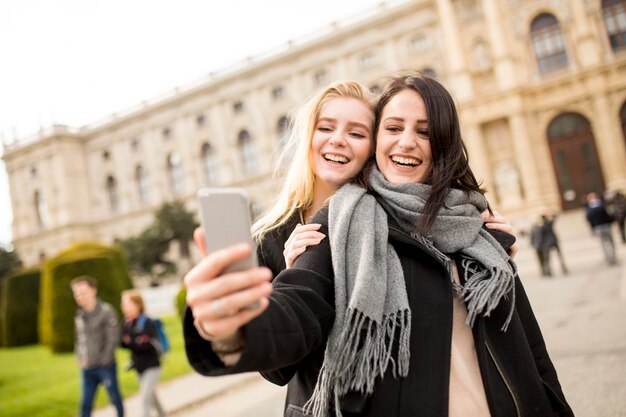 Due belle giovani donne facendo selfie in città