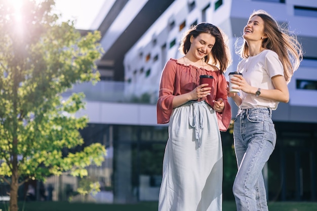 Due belle giovani studentesse felici in abiti casual in denim si rilassano nel parco del college