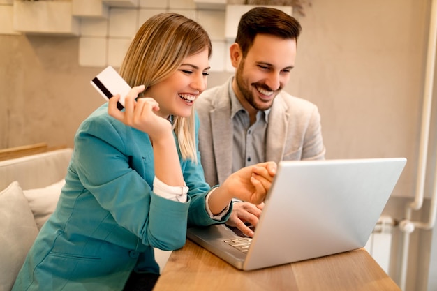 Due belle persone di affari sorridenti che lavorano al computer portatile in una pausa al caffè.