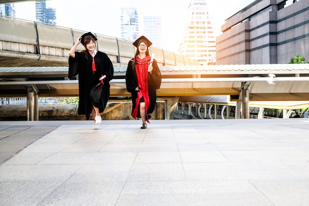 Due belle ragazze asiatiche abbracciano la cerimonia di laurea