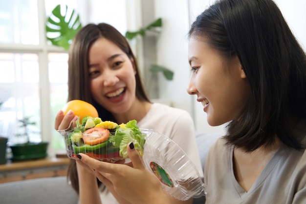 Due belle ragazze asiatiche sono a dieta mangiando insalata.