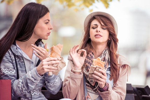 Due belle ragazze che mangiano panino dopo lo shopping