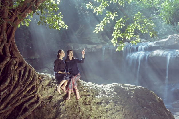 Due belle ragazze che si rilassano vicino alla cascata.