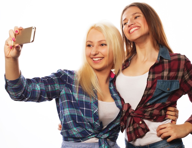 Due belle ragazze hipster che prendono selfie. Isolato su sfondo bianco.