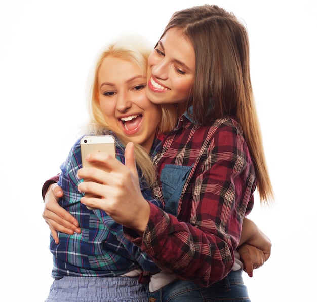 Due belle ragazze hipster che prendono selfie. Isolato su sfondo bianco.