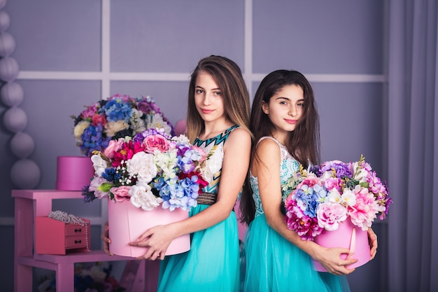 Due belle ragazze in abiti blu con decorazioni di fiori in cesti
