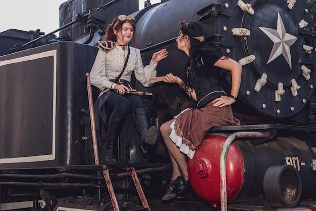 Due belle ragazze in abiti steampunk sullo sfondo del treno