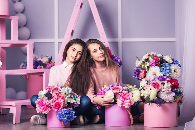 Due belle ragazze in jeans e maglione rosa con decorazioni di fiori in cesti