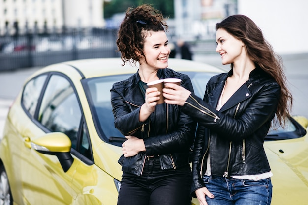 Due belle ragazze moderne sono in piedi in macchina e divertirsi