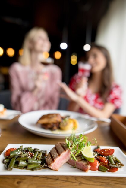 due belle ragazze sorridenti bevono cocktail e mangiano cibo delizioso in un bar