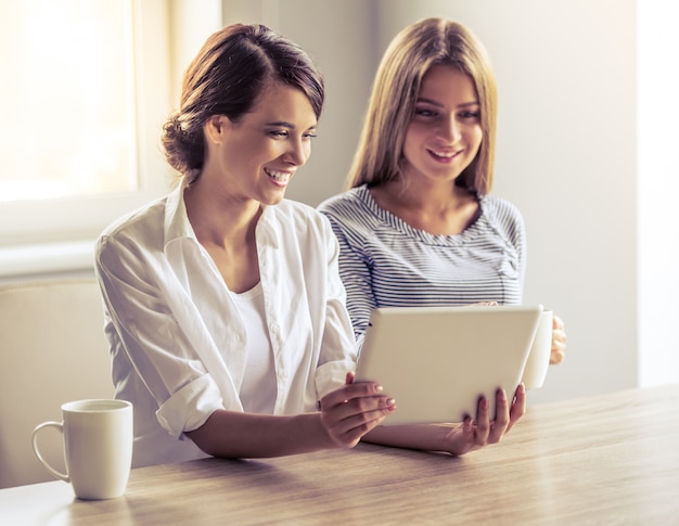 Due belle ragazze stanno usando una tavoletta digitale.