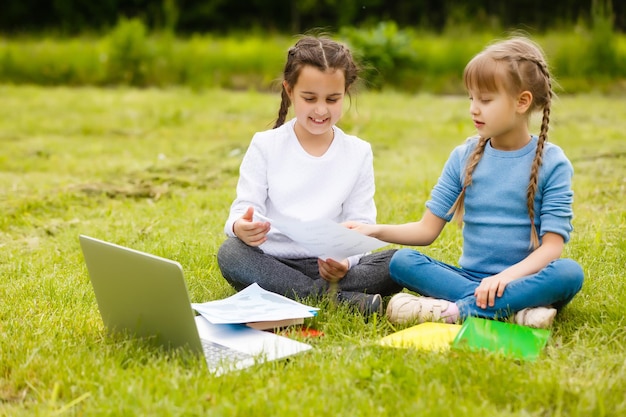 Due belle sorelle fanno i compiti durante la quarantena. I bambini usano i gadget per imparare. Istruzione, didattica a distanza, scuola a casa durante la quarantena