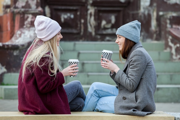 due bellissime ragazze con i capelli lunghi che bevono caffè in città