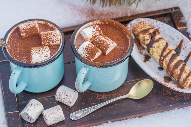 Due bevande calde al cacao su un letto di neve e uno sfondo bianco da vicino
