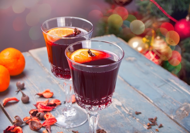 Due bicchiere di vino con Natale vin brulè con spezie e frutta su un tavolo in legno rustico.