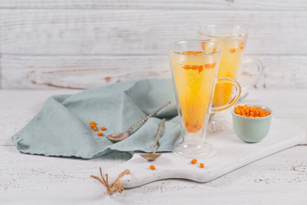 Due bicchieri alti con colorato tè caldo all'olivello spinoso con bacche fresche di olivello spinoso