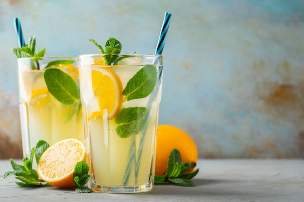 Due bicchieri con cocktail di limonata o mojito con limone e menta, bevanda o bevanda rinfrescante fredda