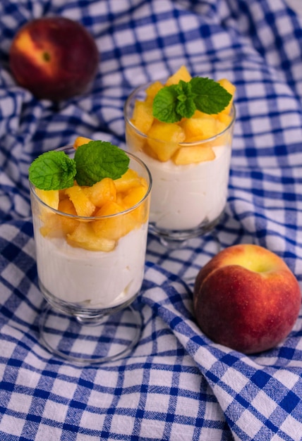 Due bicchieri con yogurt alla pesca sullo sfondo di una tovaglia blu