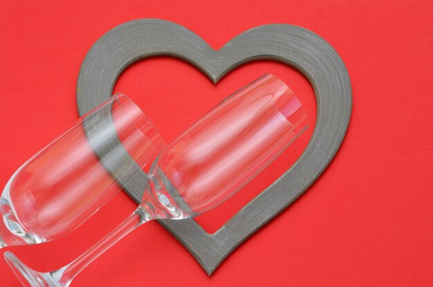 Due bicchieri da vino e cornice a forma di cuore su sfondo rosso romantico
