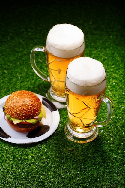 Due bicchieri di birra e hamburger sull'erba verde
