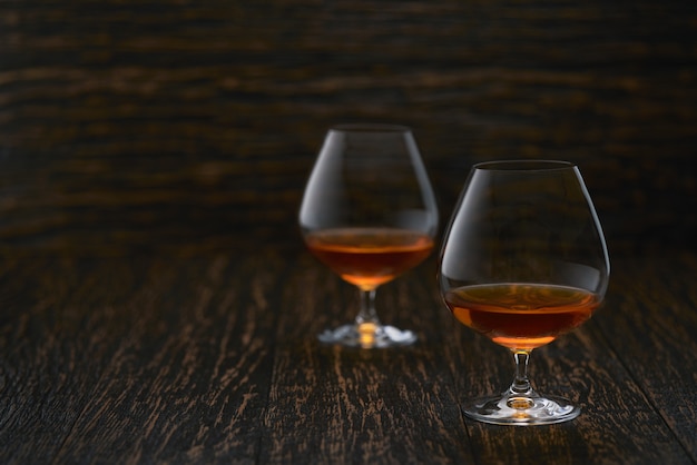 Due bicchieri di brandy o cognac su un tavolo di legno con spazio di copia.