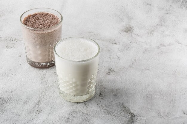 Due bicchieri di cacao ghiacciato o latte al cioccolato isolati su fondo di marmo luminoso. Vista dall'alto, copia spazio. Pubblicità per menu bar. Menu della caffetteria. Foto orizzontale.