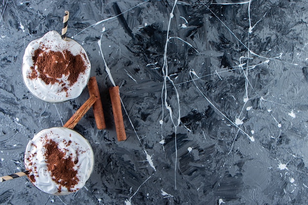 Due bicchieri di caffè con panna montata su superficie di marmo.