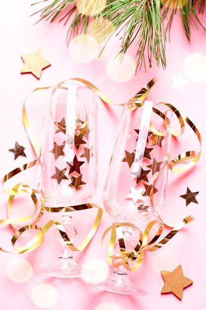 Due bicchieri di champagne con coriandoli e stelle filanti nei colori rosa e oro